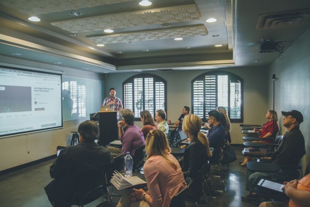 A presenter speaking to seated participants in a host-company workshop